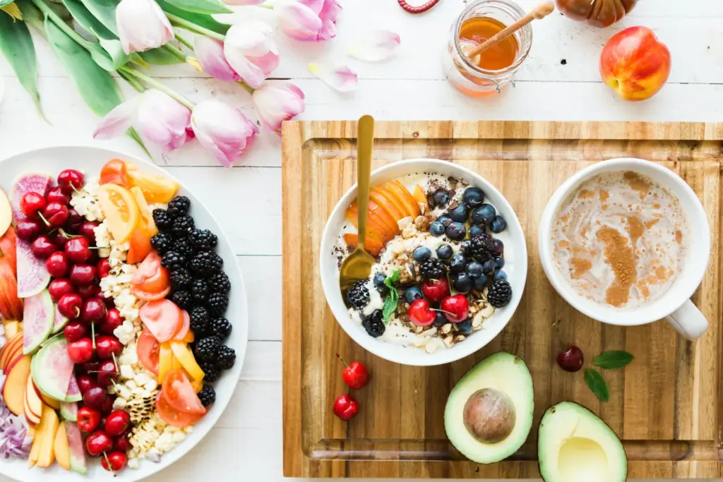 Breakfast table with a fruit and yoghurt bowl, avocado, honey and pink tulips