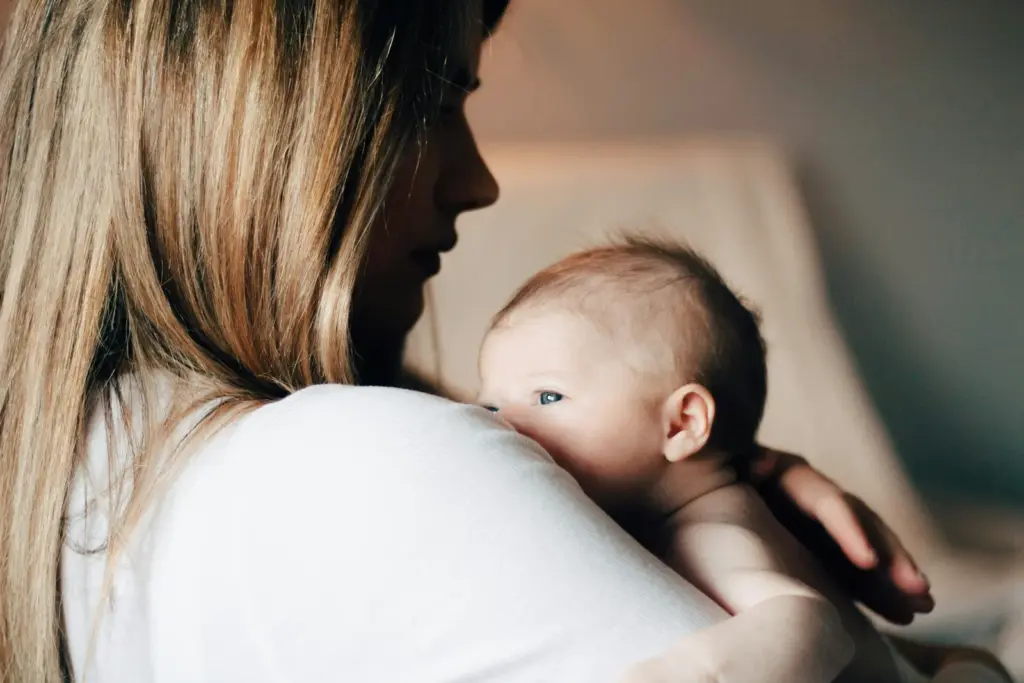 Mother in a white shirt holding her baby close against her chest